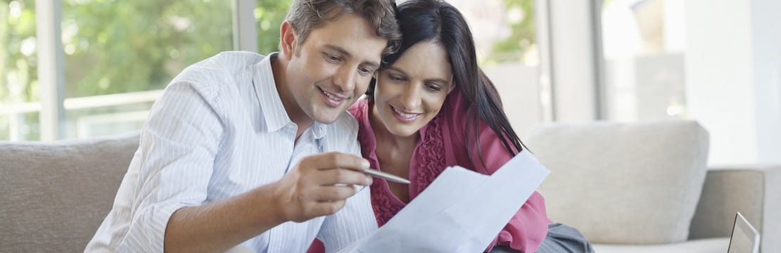 Couple reviewing documents on their couch at home.